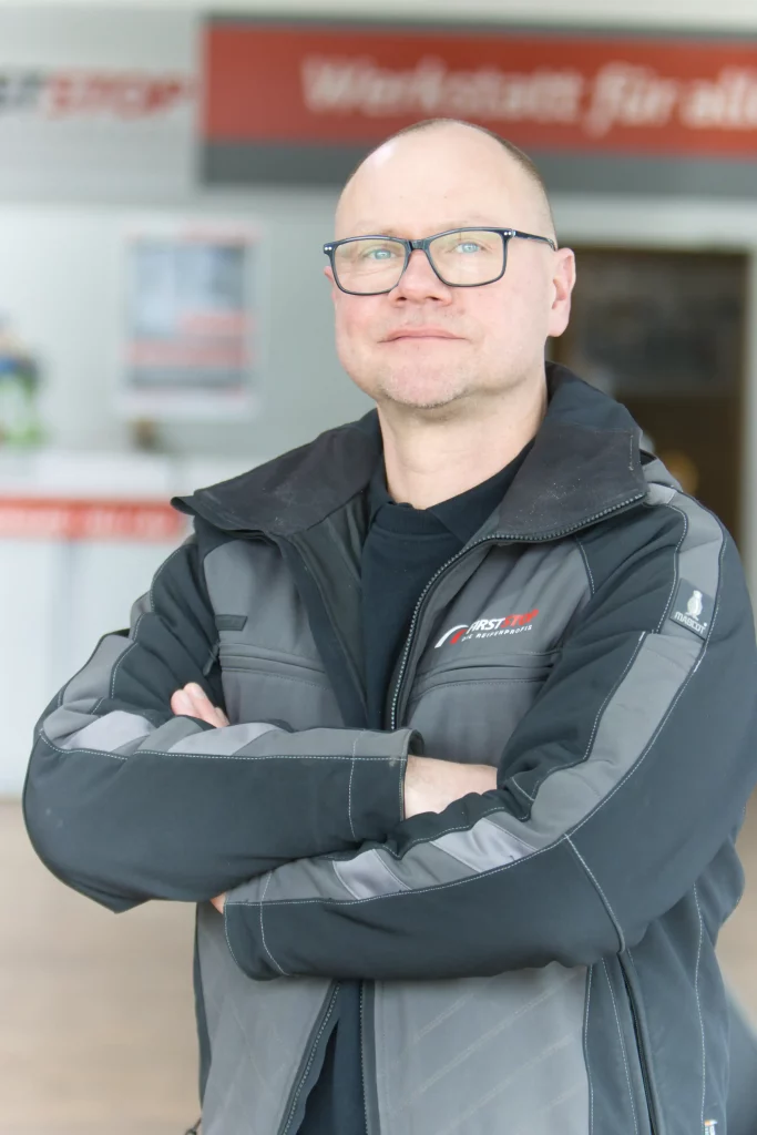 Mitarbeiter in Arbeitskleidung von FIRSTSTOP Schwerin steht vor einem Empfangsbereich.